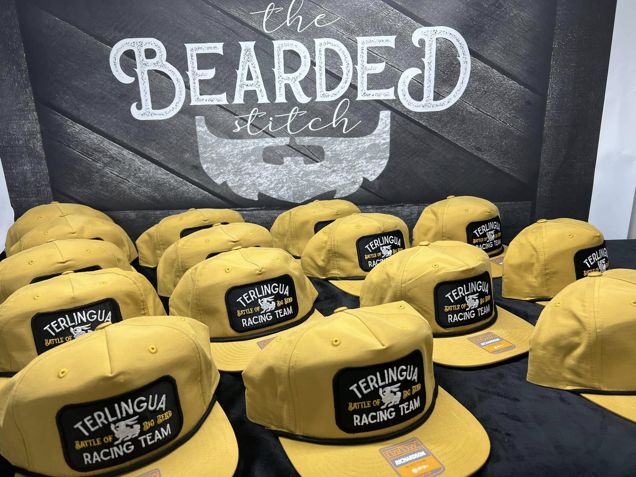 Yellow custom racing team hats with embroidered patches displayed at Bearded Stitch